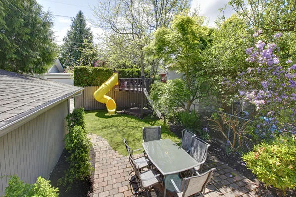 Garten mit Kinderbaumhaus und Tisch mit Stühlen. — Stockfoto