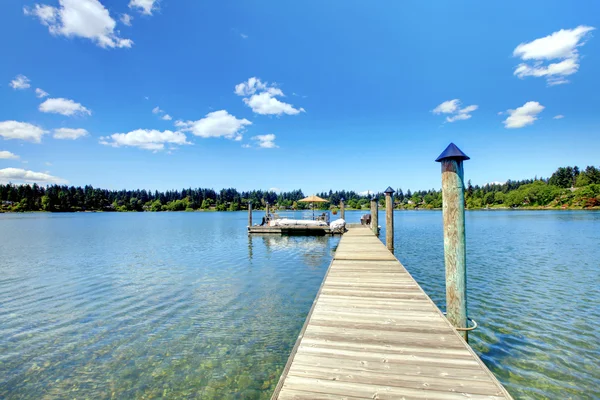Lake with long wood pier and private party raft. — Stock Photo, Image
