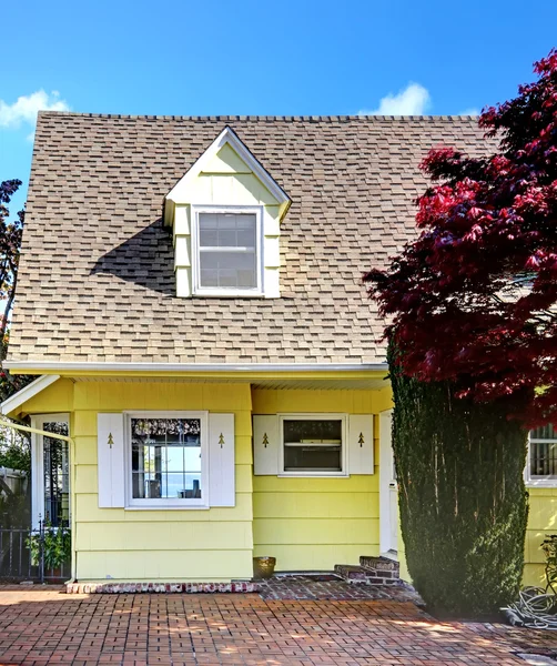 Pequeña casa amarilla con vista al agua y arce rojo . — Foto de Stock