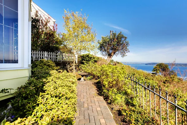 Pequeña casa amarilla con vista al agua y arce rojo . — Foto de Stock