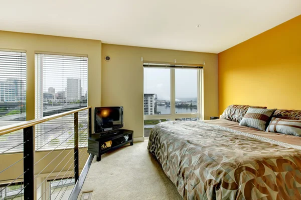 Loft lägenhet sovrum med räcke och tv. — Stock fotografie