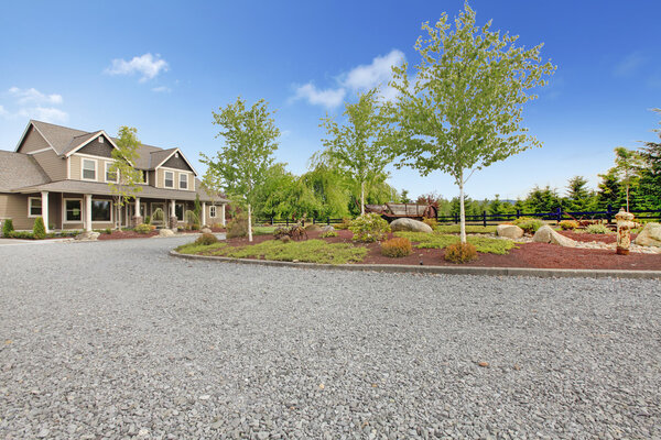 Large farm country house with gravel driveway and green landscape.