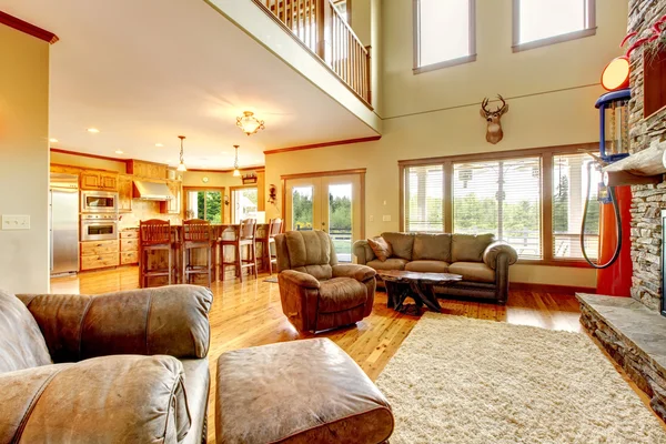 Sala de estar com teto alto, lareira de pedra e sofá de couro . — Fotografia de Stock