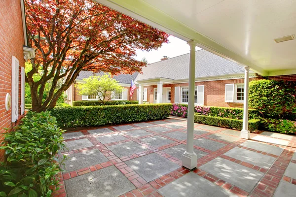 Casa vermelha tijolo com jardim Inglês e persianas janela branca . — Fotografia de Stock