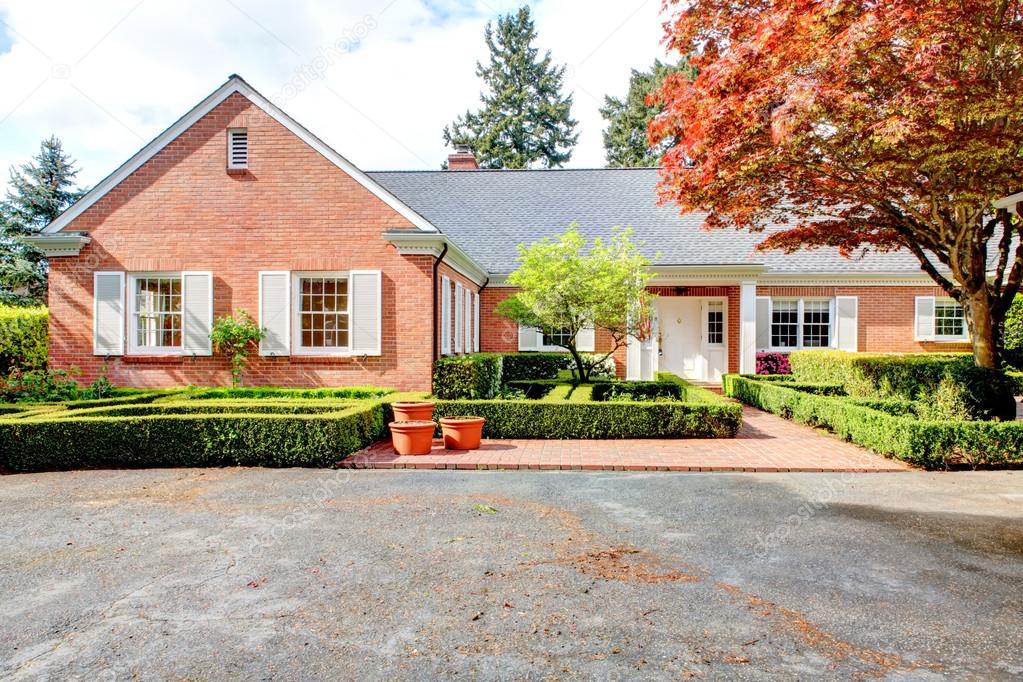 Brick red house with English garden and white window shutters.