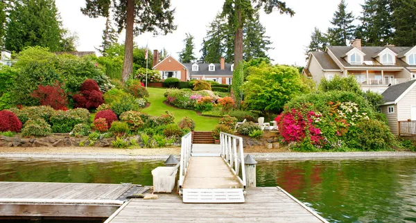 Casa de ladrillo rojo con jardín inglés y persianas blancas . — Foto de Stock