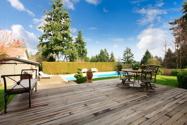 Wooden back poch overlooking swimming pool and trim — Stock Photo, Image