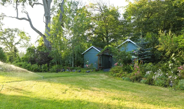 Bloeiende boerderij achtertuin met loodsen en tuin Huis — Stockfoto