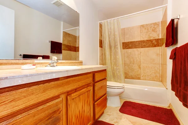 Salle de bain aux couleurs chaudes avec serviettes rouges et tapis — Photo
