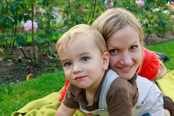 Lycklig pojke och mamma spelar i parken under solnedgången. — Stockfoto