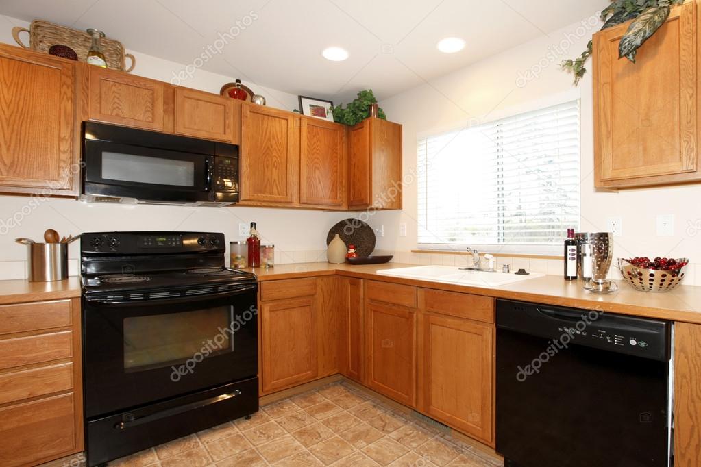 Brown kitchen cabinets with black appliances