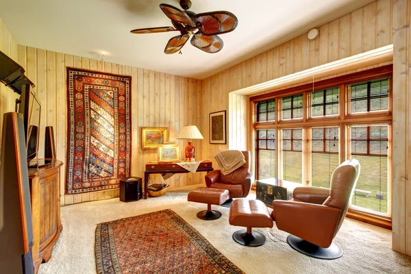 Furnished wood plank paneled room with rugs — Stock Photo, Image