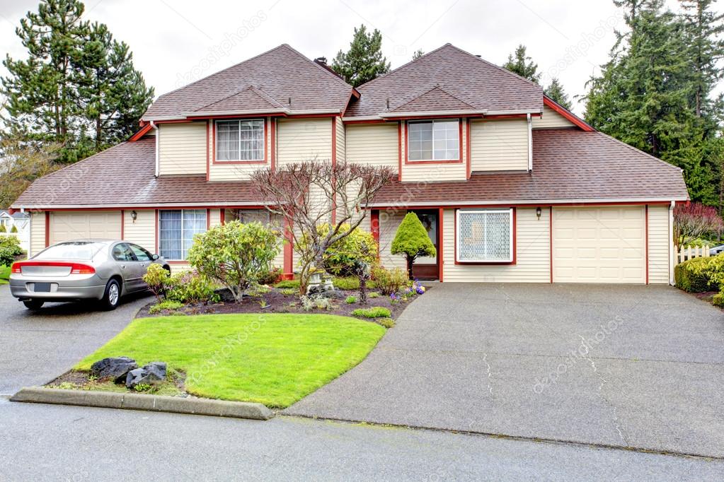 Big house with two cars garage. Siding exterior with red corner 