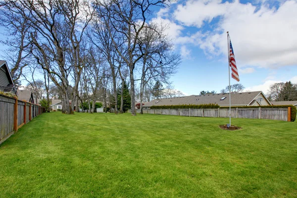 Prostorná půda oblast s zelený trávník a americká vlajka — Stock fotografie