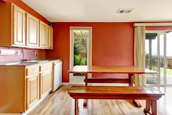 Rotes Esszimmer mit rustikalem Tisch und Bank — Stockfoto