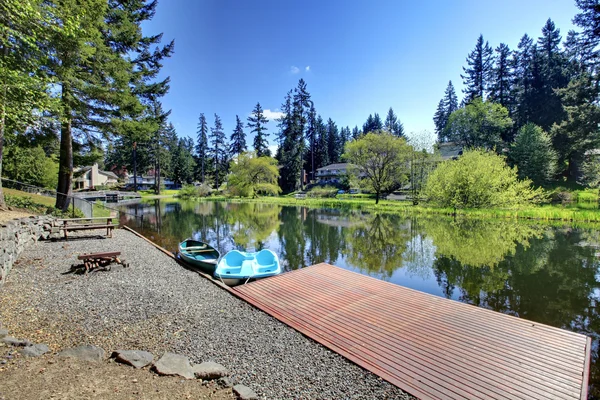 Private dock with boats and patio area with rustic table — Stock Photo, Image