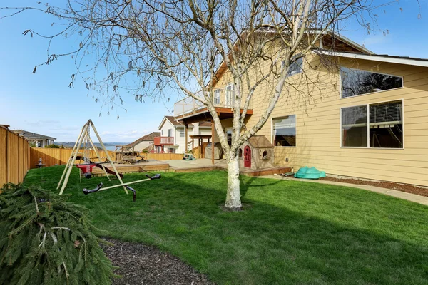Casa patio trasero con cubierta de madera y parque infantil — Foto de Stock