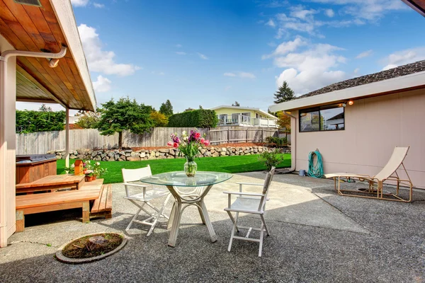 Casa exterior. Patio trasero con mesa de vidrio y sillas — Foto de Stock