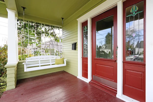 Vchodové verandě v červené a zelené barvě s visí houpačka — Stock fotografie