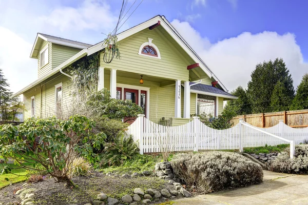 Exterior de casa verde claro con porche de columna y valla blanca — Foto de Stock