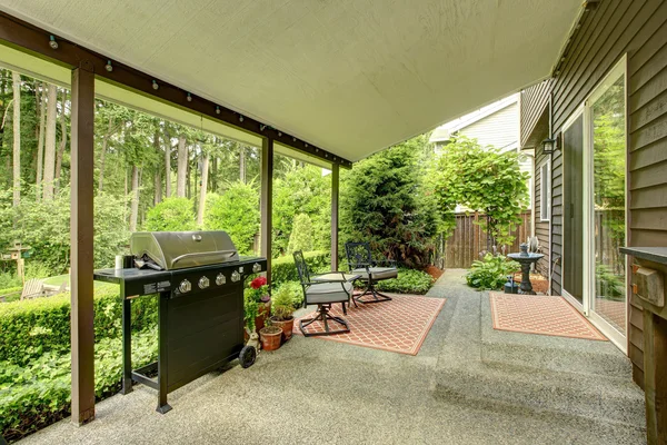 Terrasse couverte avec barbecue et chaises en fer — Photo
