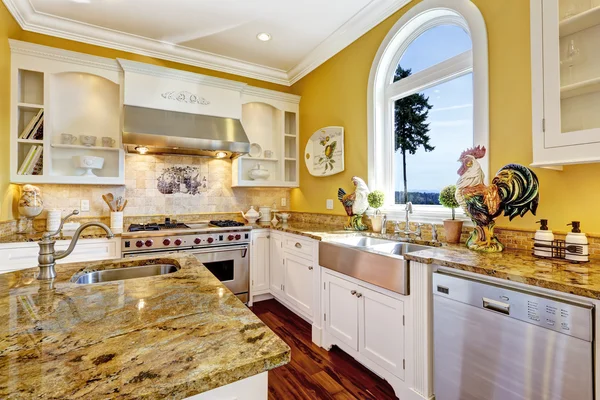 Zářivě žlutá kuchyň pokoj s žulovými vrcholy a obloukovým oknem — Stock fotografie