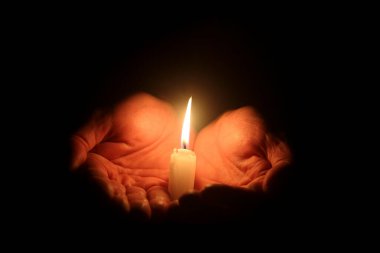 Siyah üzerinde yanan mum olan erkek elleri