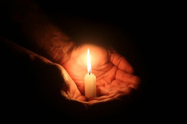 Siyah üzerinde yanan mum olan erkek elleri