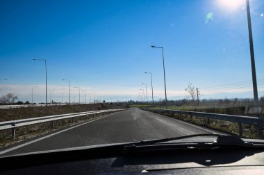 Güneşli bir günde boş bir yolda araba sürmek.