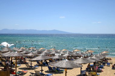 popular beach resort with sunbeds and straw umbrellas, sunny day and full of people