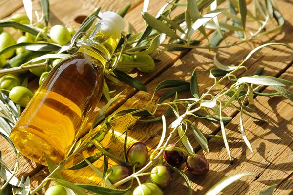 bottle of olive oil with olive tree branches on old wooden table