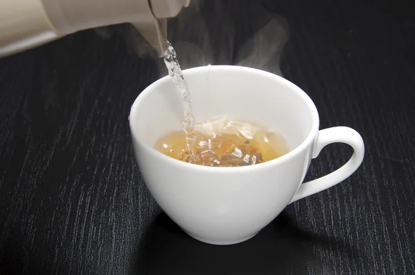 Наливание воды для вашей чашки чая — стоковое фото