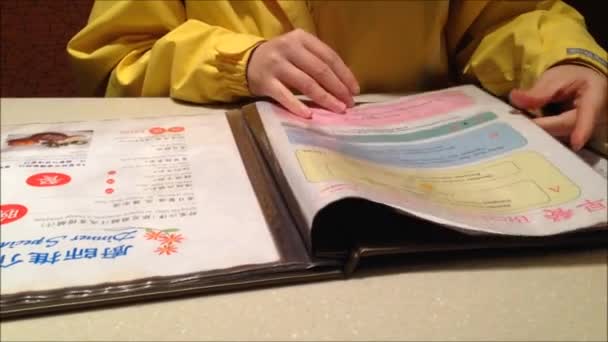 Женщина проверяет меню в ресторане — стоковое видео