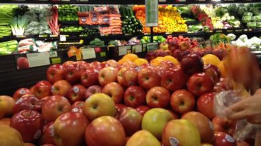 kadın markette taze kırmızı elmalar seçme