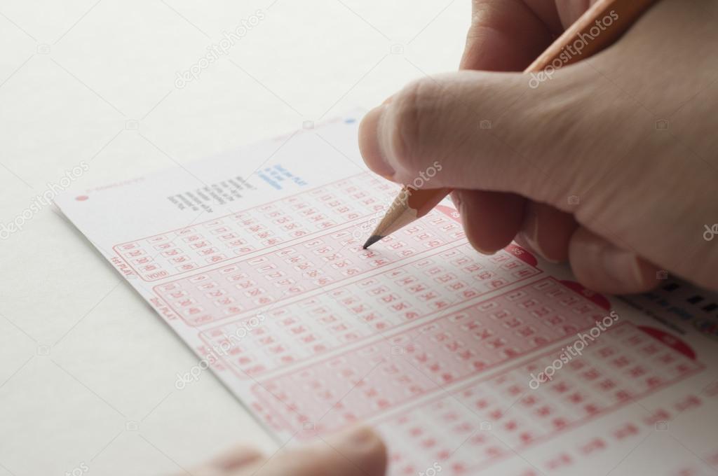 Person marking number on lottery ticket with pen