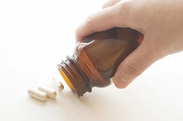 Pouring capsules from a pill bottle — Stock Photo, Image