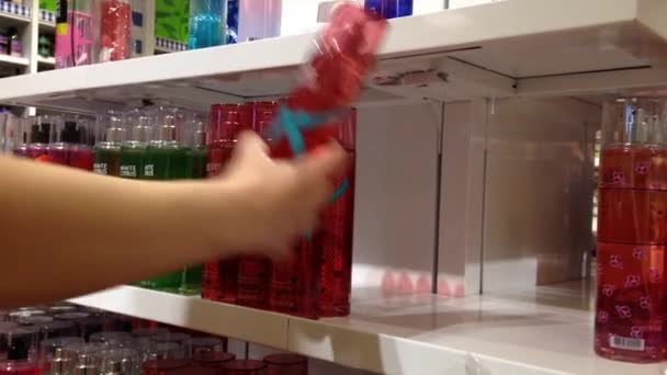 Mujer eligiendo aroma líquido en el estante de exhibición — Vídeo de stock