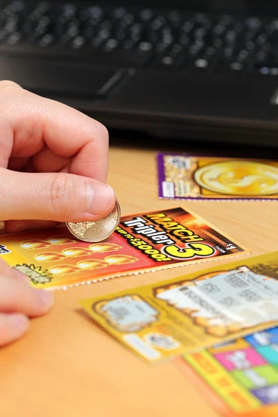 Scratching lottery tickets with computer background.