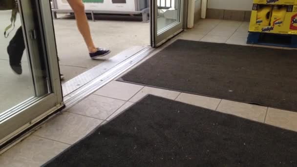 Люди с корзиной идут через двери супермаркета — стоковое видео