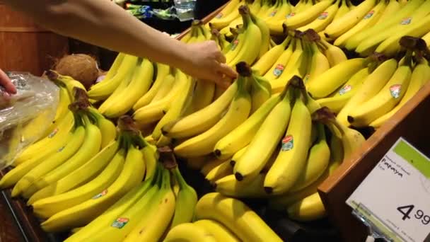 Vrouw selecteren van verse bananen in de supermarkt produceren departement. — Stockvideo