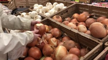 Woman selecting onion in grocery store produce department with 4k resolution