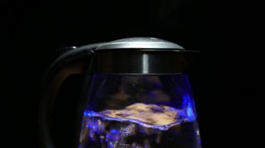 Tea kettle with boiling water on a black background with 4k resolution
