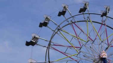 The motion of an empty riding Ferris wheel against a blue sky with 4k resolution