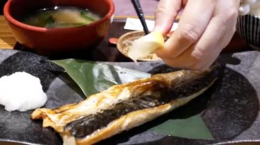 The motion of a woman squeezing lemon juice on the fish before eating inside a Japanese restaurant with 4k resolution