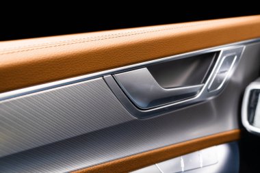 Araba kapısı, kahverengi deri desenli ve dikişli lüks modern arabanın içinde. Düğme kontrolünü değiştir. Modern araba iç dekorasyonu. Turuncu delinmiş deri.