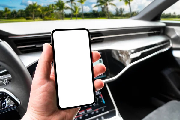 Driver hand using smartphone in car. Smartphone in a car use for Navigate or GPS. Mobile phone with isolated white screen. Blank empty screen. copy space. Empty space for text.