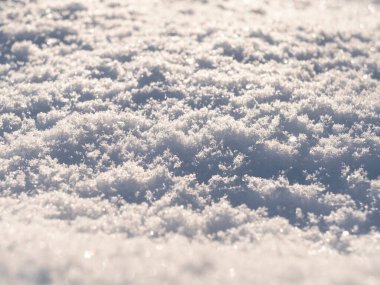 Macro gün batımında taze beyaz karın arka planını çekti. Kar taneleri dokusu. Kar dokusu kış arka planı. Bokeh güneş ışınlı parlak kar.