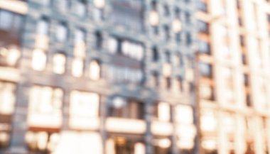 Gün batımında dış görünüşü aydınlanmış, soyut, bulanık bina. Bokeh ışığıyla bulanık modern bina ve güneş ışınlarıyla çözünmüş noktalar. Arkaplan için bulanık pencereler