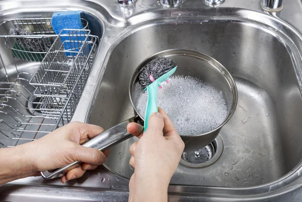 Nettoyage de la casserole en acier inoxydable avec brosse à tampon en acier — Photo