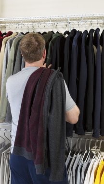 Mature man making decision of which sweater to wear clipart